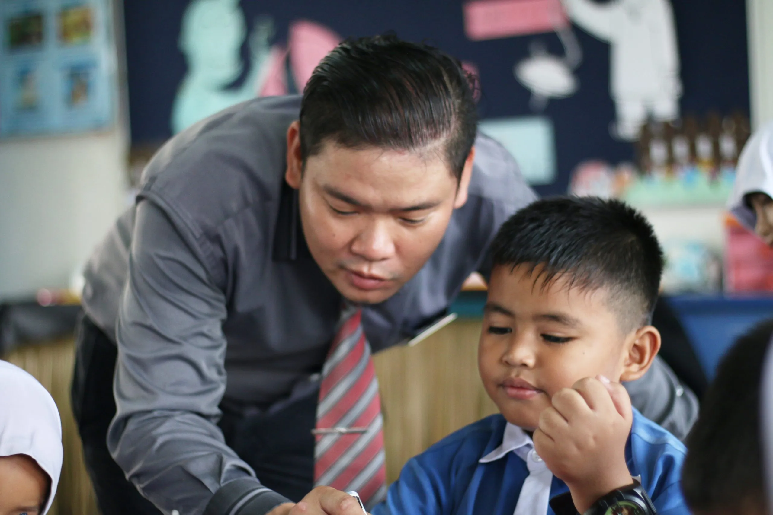 A teacher leaning in to help a pupil with his work