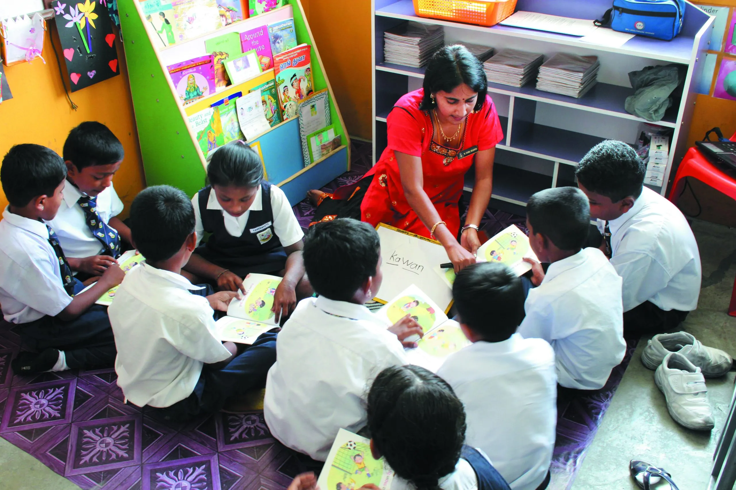 A teacher reading with a group of pupils seated on the classroom floor