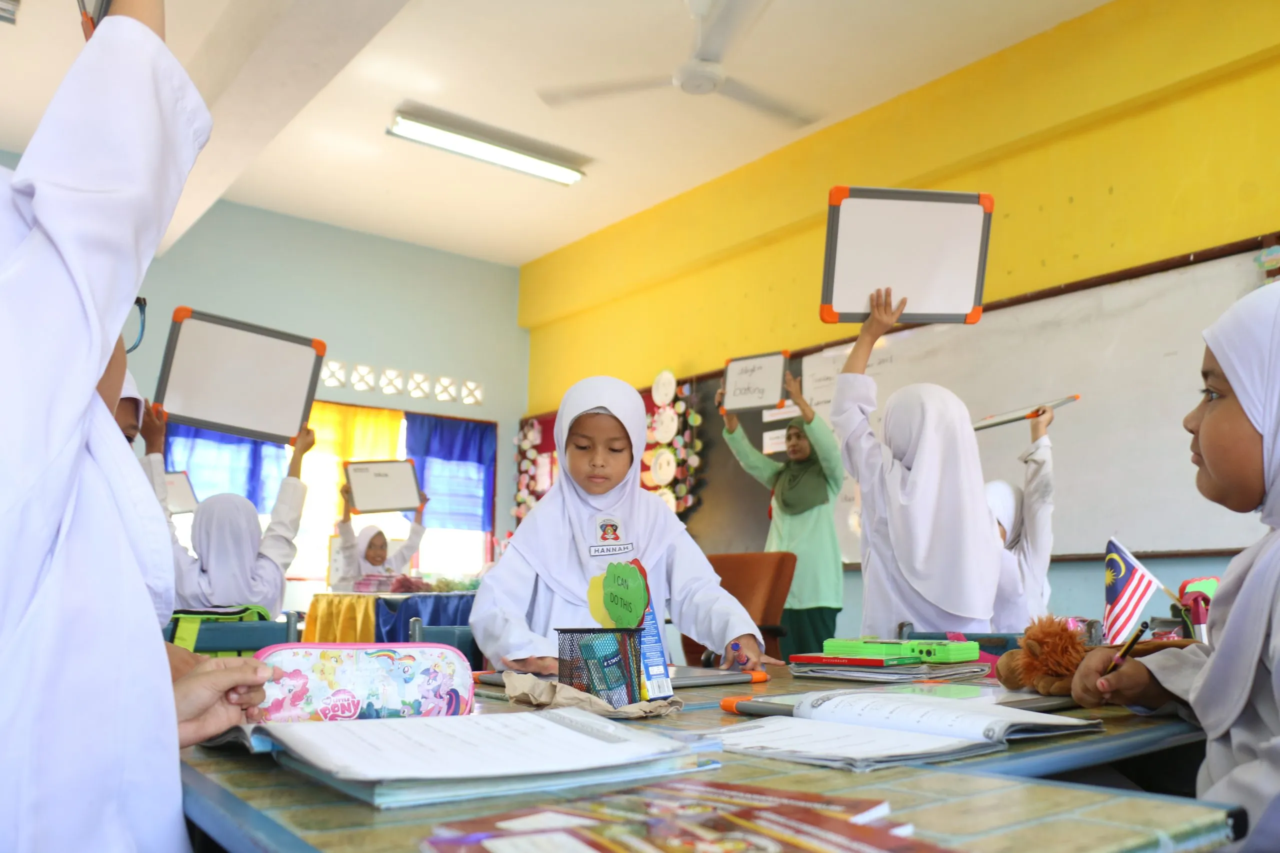 Primary school pupils holding up their work in a classroom