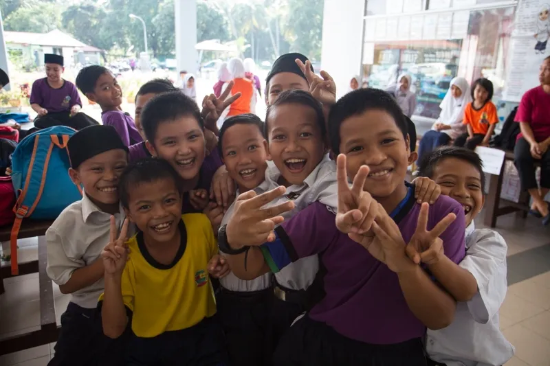 Smiling primary school pupils making peace signs