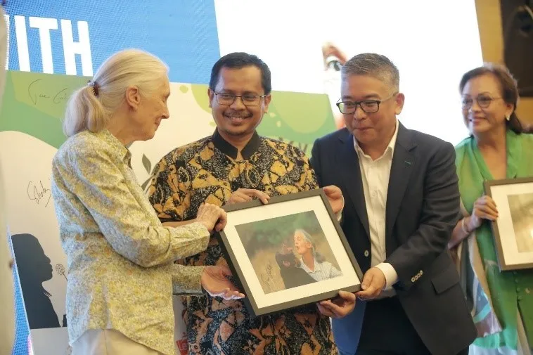 Four people holding a framed picture at an event
